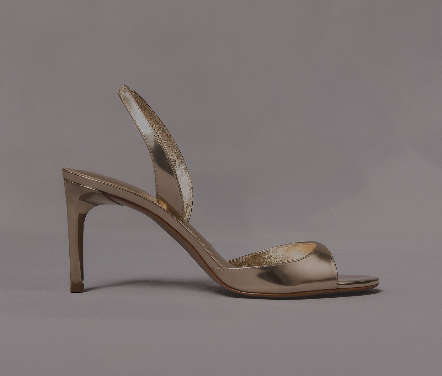 Metallic gold ankle-strap sandals with open toes and high heels.