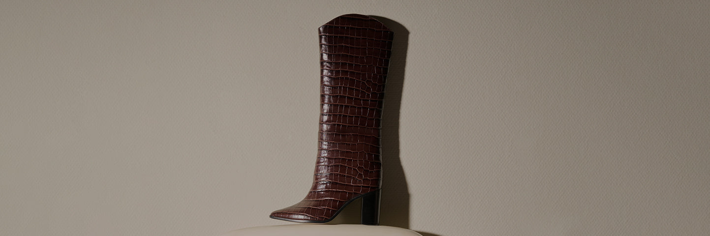 Promotional banner featuring a brown crocodile-embossed knee-high boot with a block heel against a neutral background, with the text ‘Best Sellers’ and a subtitle highlighting bestselling shoe style