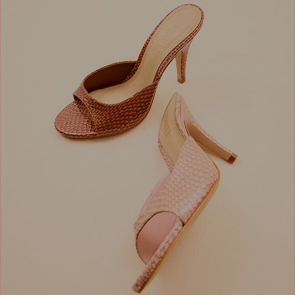 Strappy high-heel mules in a light neutral color, photographed in a studio setting.