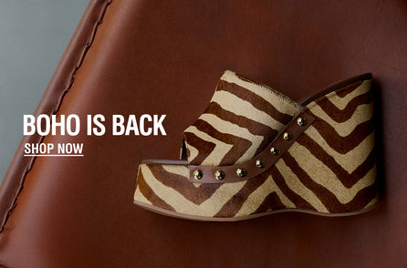 A bohemian-style platform sandal with a zebra pattern and stud accents is placed on a brown leather surface. Text reads 