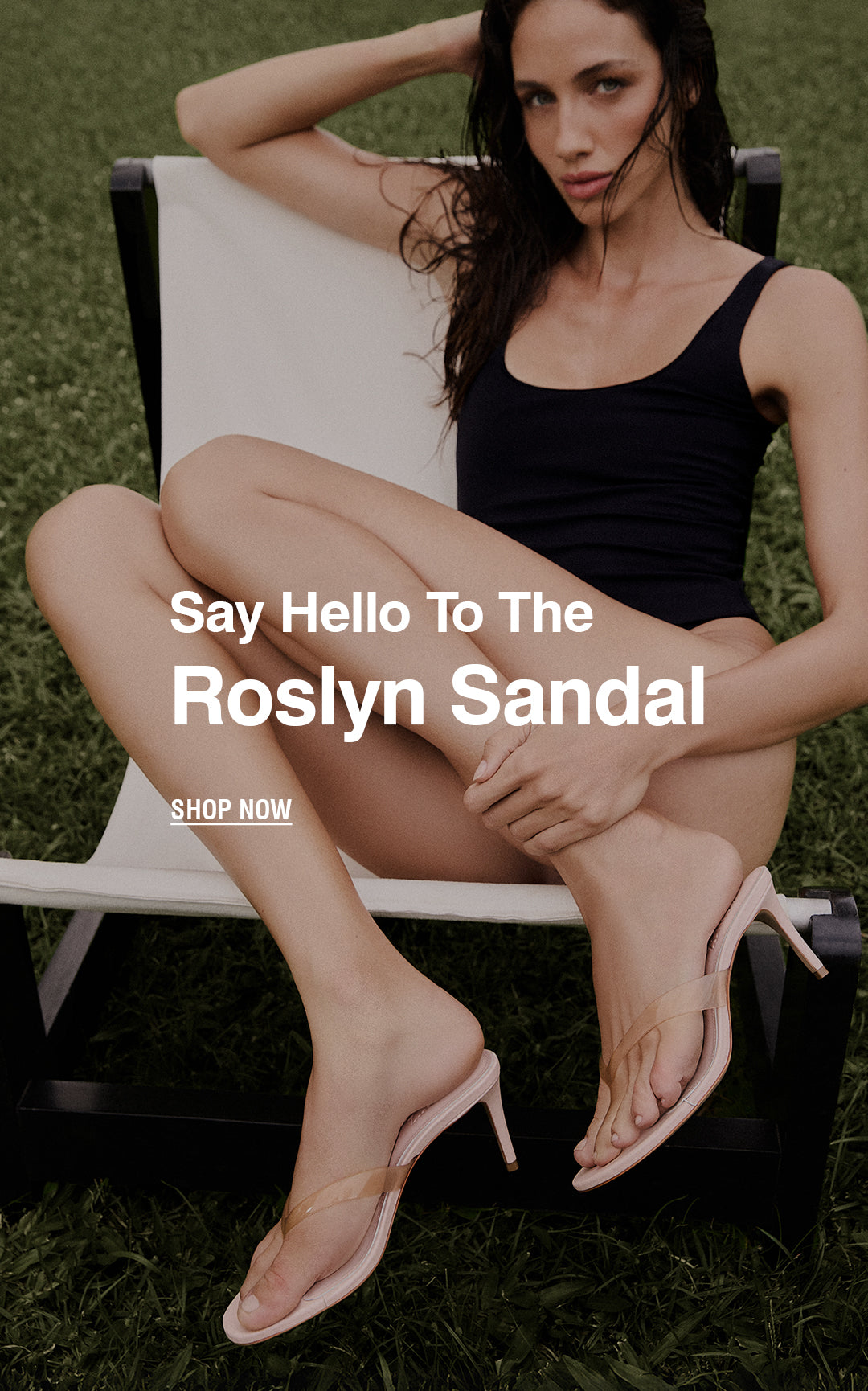 A woman in a black one-piece swimsuit reclines on a white lounge chair on grass, showcasing pink heeled sandals. Text reads, "Say Hello to The Roslyn Sandal.”