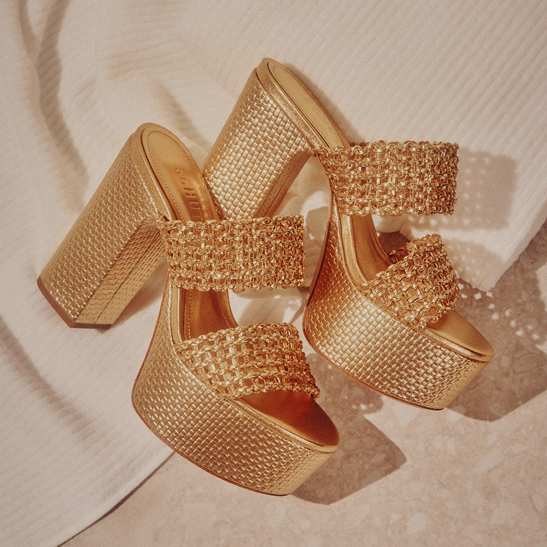 Goldplatform high heels with woven straps and textured soles, placed on alight-colored surface with a white, ribbed fabric backdrop, exuding luxury andelegance.