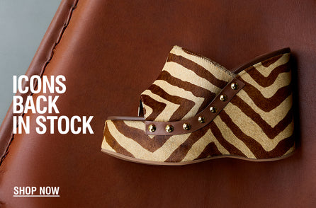 Zebra-patterned wedge sandal with gold studs on brown leather surface. Text reads 