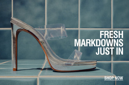 Silver high-heeled shoe with clear straps on a blue tiled surface. Text reads 