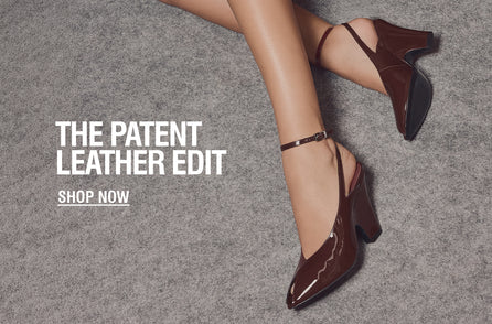 Close-up of a woman's legs wearing shiny brown patent leather heels with ankle straps on a gray carpet. Text reads, 