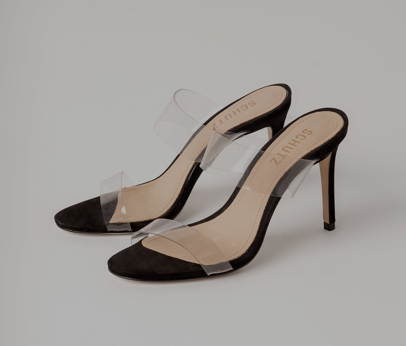 Black suede high-heel slide sandals with clear PVC straps and a round toe.