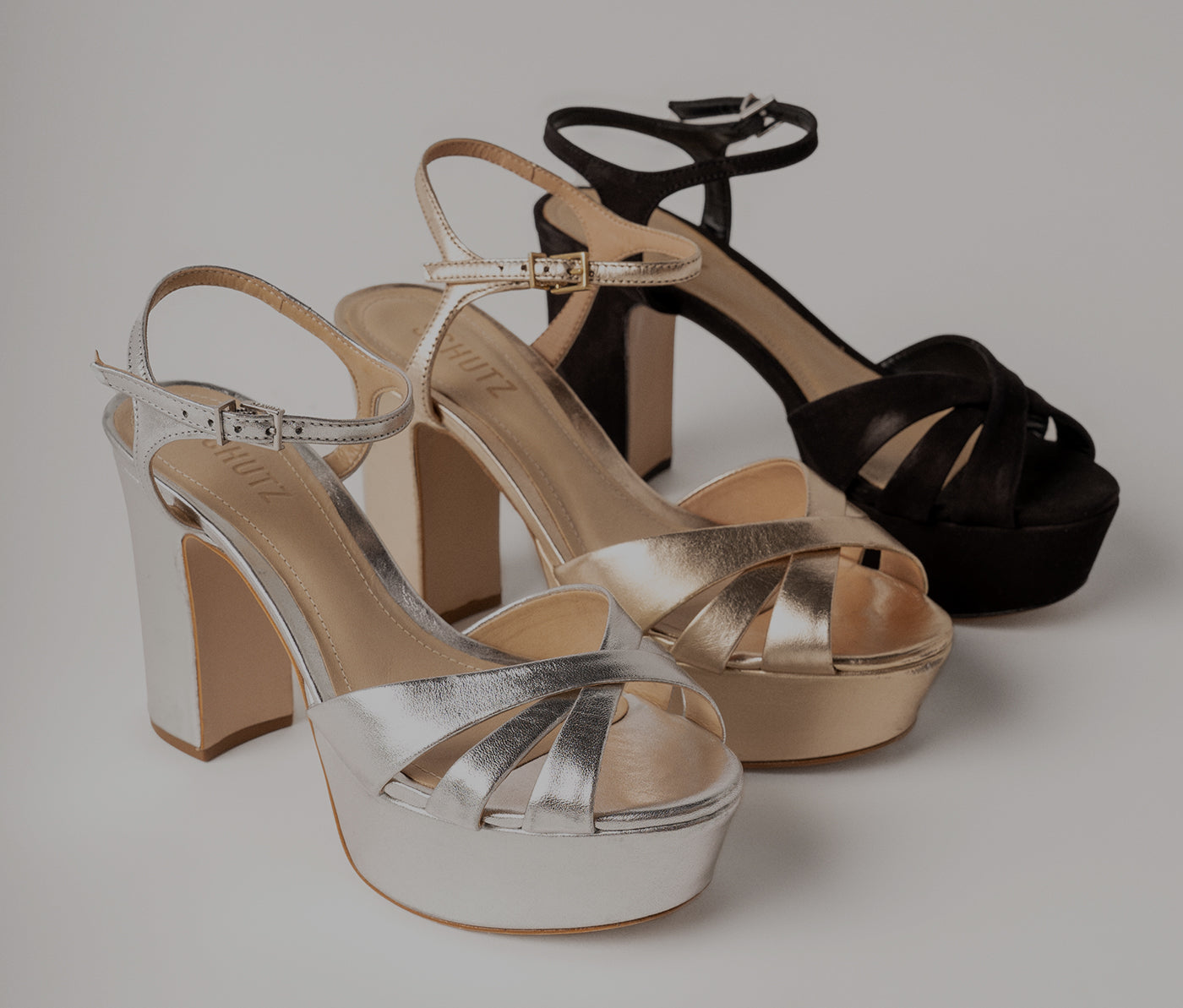 Silver, gold, and black platform sandals with block heels and ankle straps.