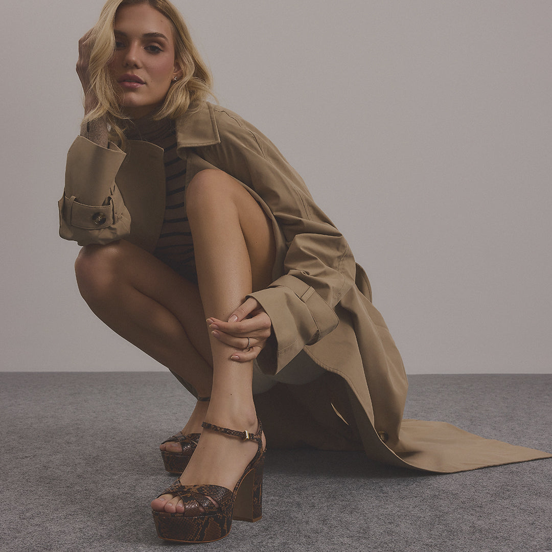 Model wearing brown snake-print platform high heel sandals with a neutral trench coat.