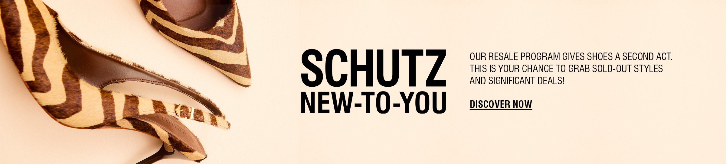 A person's legs and feet are visible on a crosswalk. They are wearing a pair of silver metallic high-heel mules with two thin straps over the foot. The text "SCHUTZ NEW-TO-YOU" and "DISCOVER NOW" are on the right side of the image, advertising a resale program.
