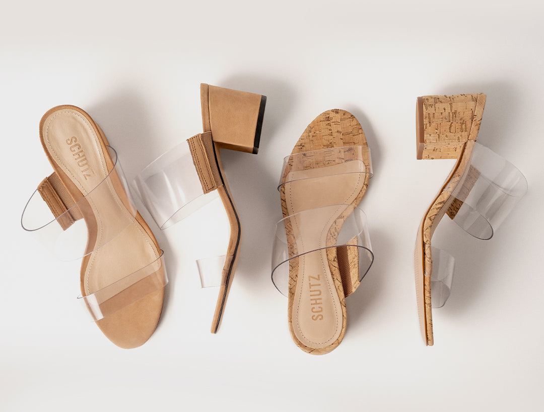 Four minimalist heeled sandals arranged on a clean white background, showing different angles of the same shoe design. The sandals feature clear transparent straps, a tan/beige block heel, and a cork-textured footbed with the brand name SCHUTZ visible.
