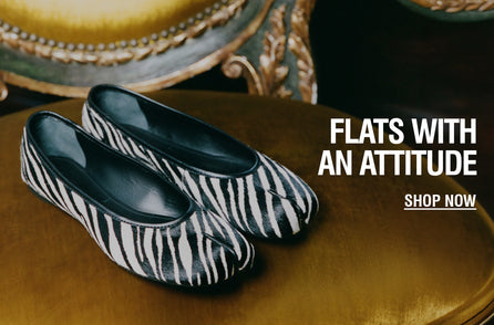 Zebra-print ballet flats with a rounded toe styled on a table, featuring a bold animal-print finish.