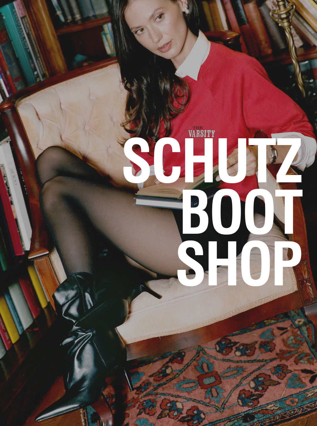 A woman sits in a tufted armchair in a book-filled room, wearing a red sweater, white collared shirt, black tights, and black pointed-toe heeled boots. Large white text across the center reads 'SCHUTZ BOOT SHOP'.