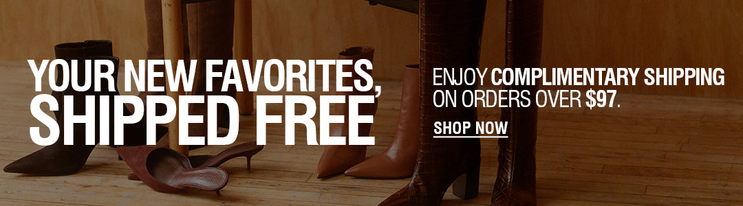 Promotional banner with large white text reading 'YOUR NEW FAVORITES, SHIPPED FREE' over a warm brown interior scene showing shoes and boots on a wooden floor, plus 'ENJOY COMPLIMENTARY SHIPPING ON ORDERS OVER $97' and a 'SHOP NOW' button.