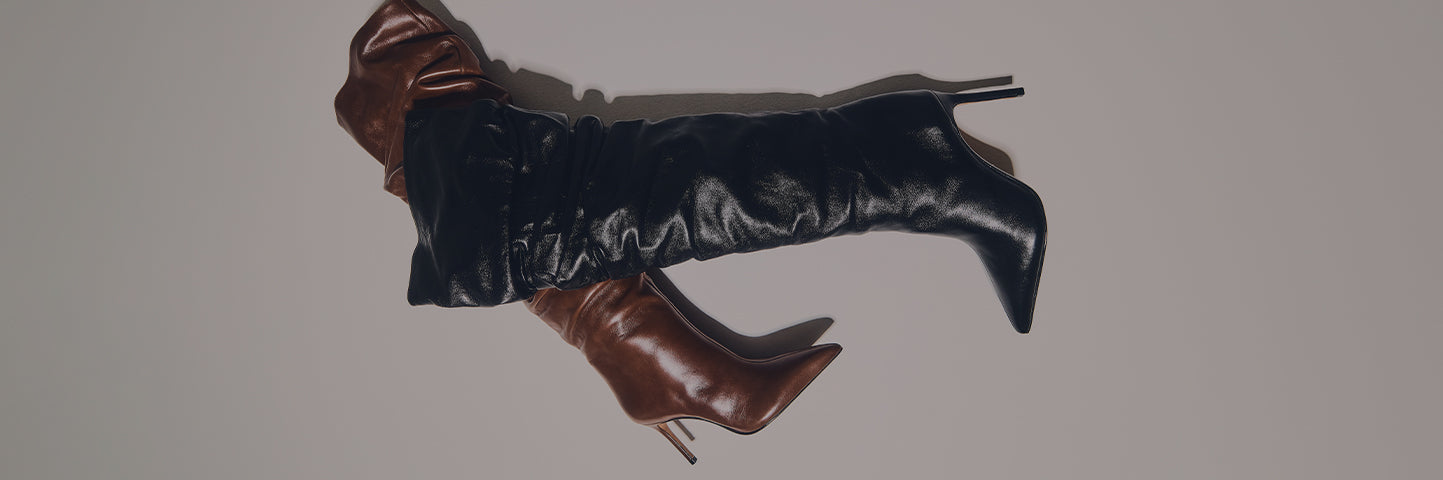 A pair of high-heeled, over-the-knee slouch boots. One boot is brown and the other is black, crossing over each other. The word BOOTS is written in large white letters on the left side of a plain gray background.