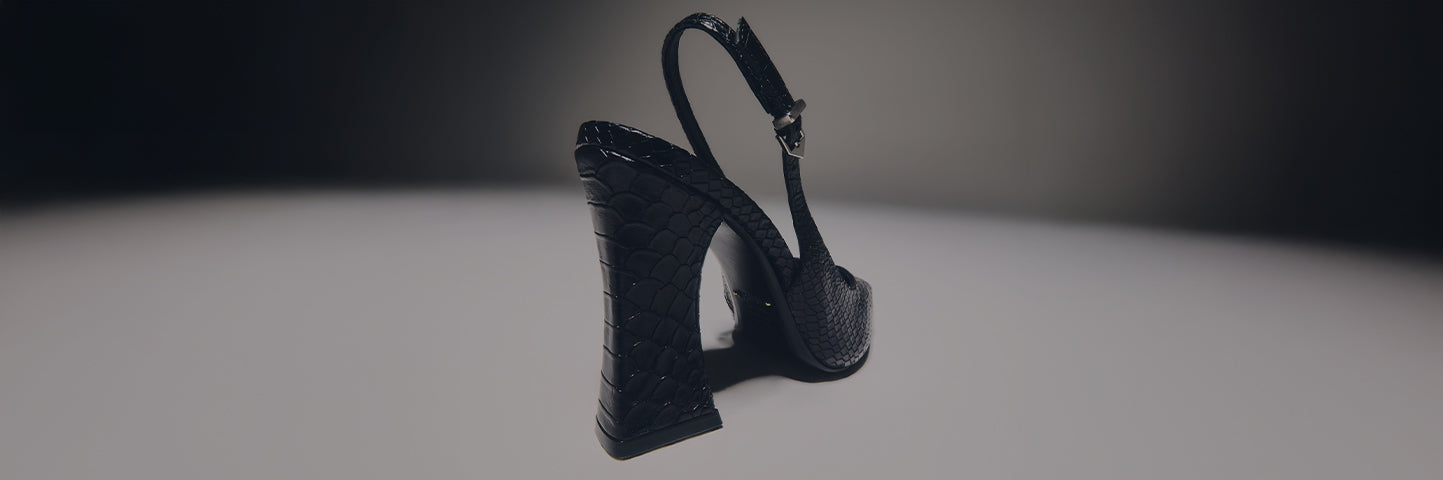 A close-up view of a black patent leather slingback shoe with a very high, chunky block heel and a platform sole. The shoe has a faux snakeskin or crocodile texture. The text BLOCK HEELS is written in large white letters on the left side, which has a dark gray background fading to a light gray on the right.