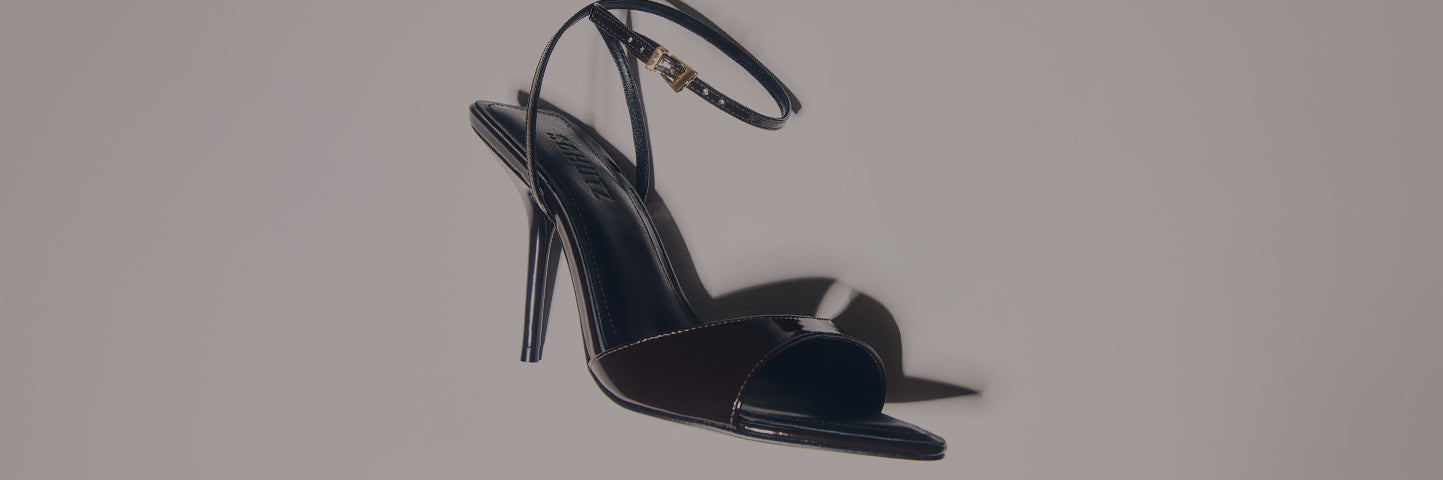 A pair of high-heel sandals in dark and glossy tones placed on a light background, with the text “HIGH HEEL SANDALS” on the left.