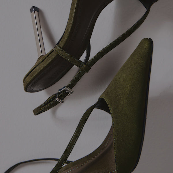 Overhead shot of two black leather slingback pumps with a deep V-cut vamp, a square toe, and a striking wedge heel, resting on a gray background.
