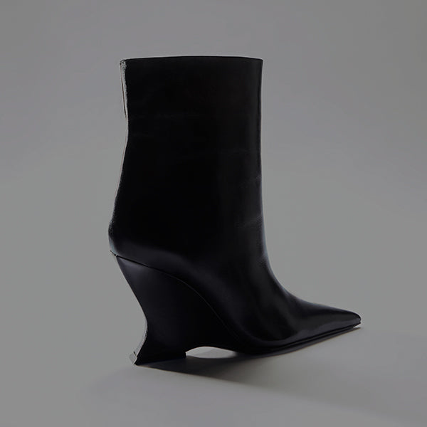 A single burgundy or dark brown leather ankle boot with a high, angular block heel and a modern square toe, posed on a light gray surface.