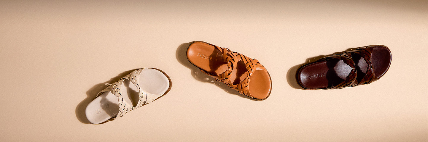 Flat lay of women’s leather sandals in neutral tones arranged on a light background, styled for a relaxed vacation mood.