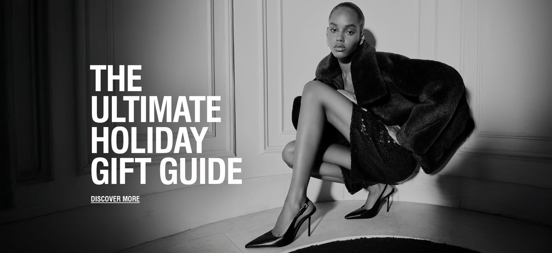 Fashion editorial-style photo of a woman sitting in a stylish pose wearing a dark fur coat, a sequined skirt, and high heels, with the text ‘The Ultimate Holiday Gift Guide’ overlaid.