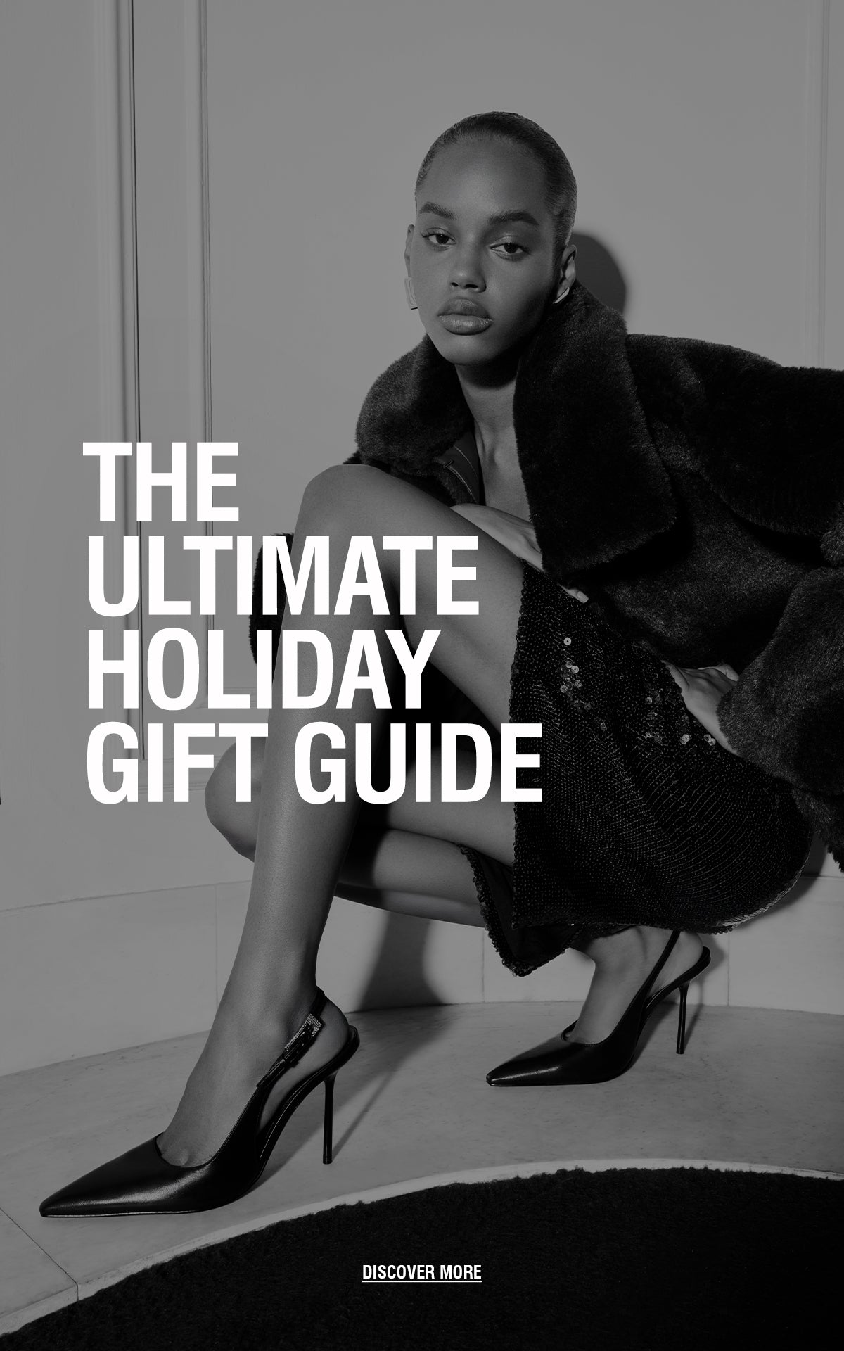 Fashion editorial-style photo of a woman sitting in a stylish pose wearing a dark fur coat, a sequined skirt, and high heels, with the text ‘The Ultimate Holiday Gift Guide’ overlaid.