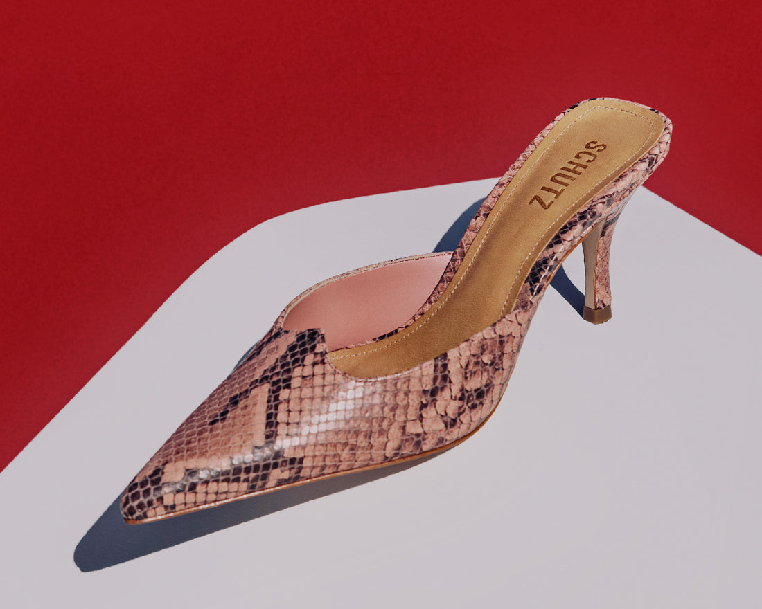 A chic snakeskin-textured mule pump from Schutz, displayed against a bold red and white background.