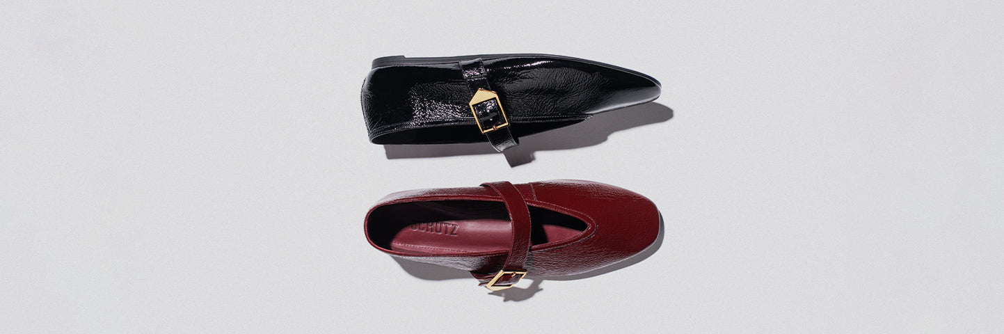 Two flat ballerina shoes side by side on a light background, one in deep red and the other in glossy black, both featuring gold buckles, with the word 'BALLERINAS' on the left.