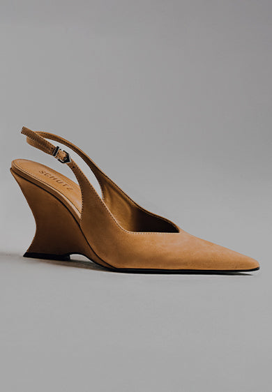 A close-up shot of two tan suede slingback wedge heels with a distinctive, sculptural, curved wedge heel. The text "SCULPTURAL HEEL" is prominent on the left side of the image.