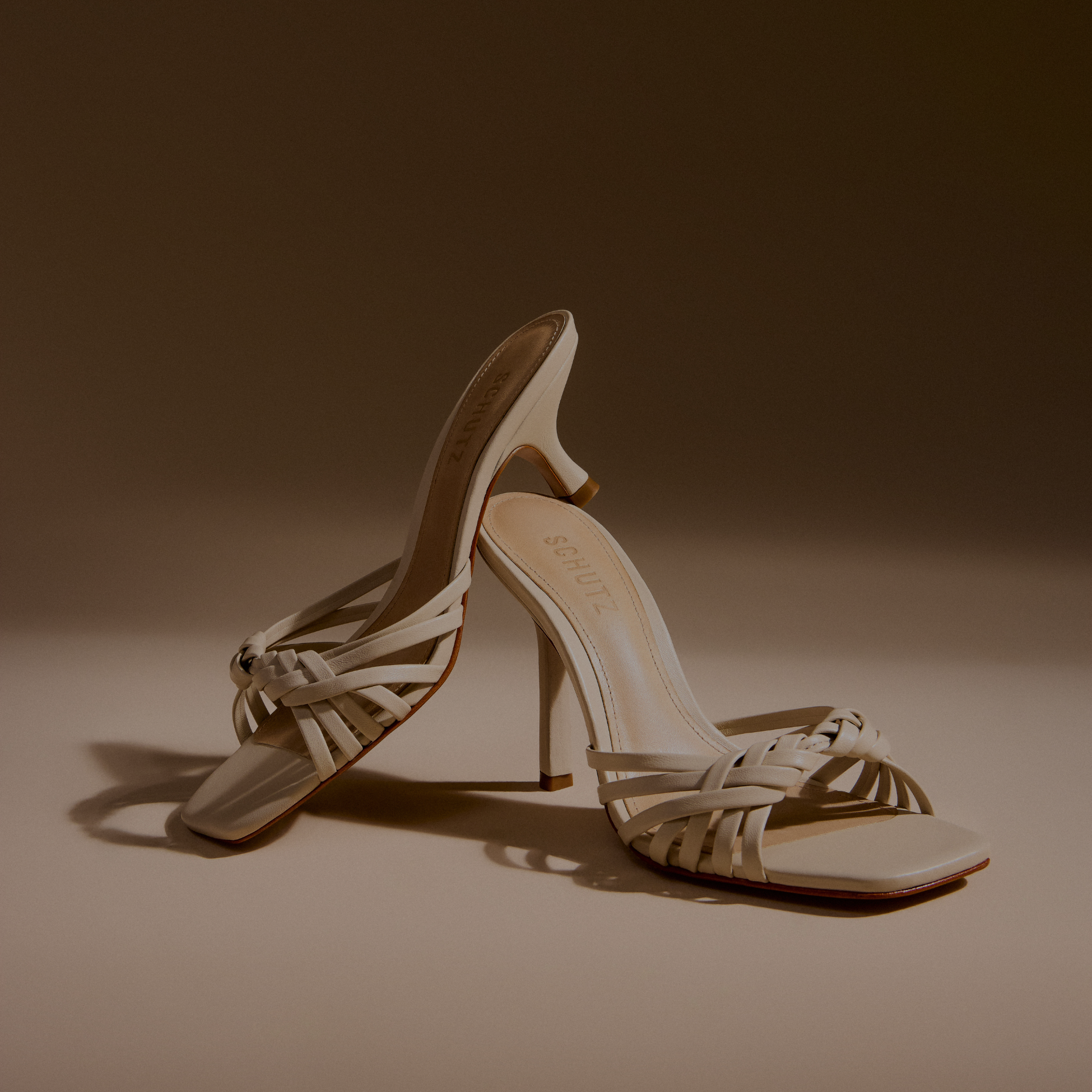 Close-up of a single black patent leather slide mule with a high, thin stiletto heel featuring a gold tone core, viewed from a high angle.