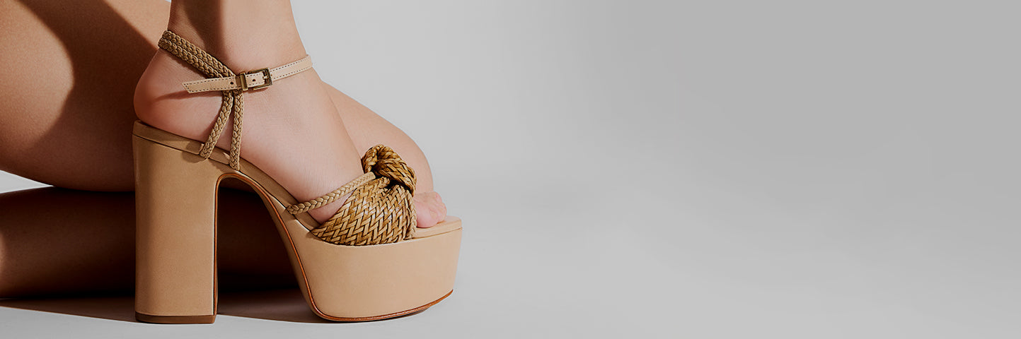 Close-up of a woman wearing beige platform block heel sandals with braided straps and ankle fastening, showcasing stylish and comfortable block heel designs.