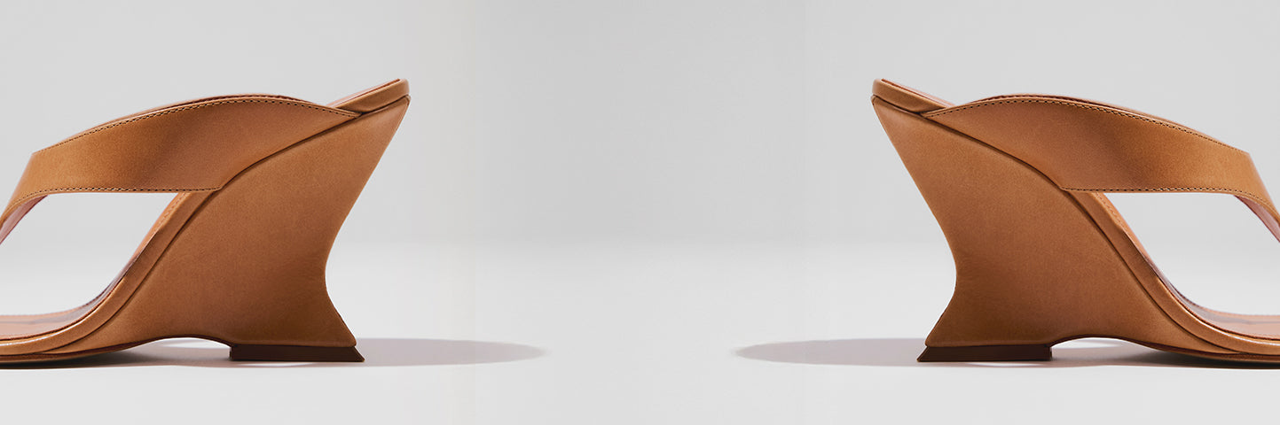 Brown sandal featuring a unique sculptural curved heel design, highlighting artistic and contemporary high heel styles.