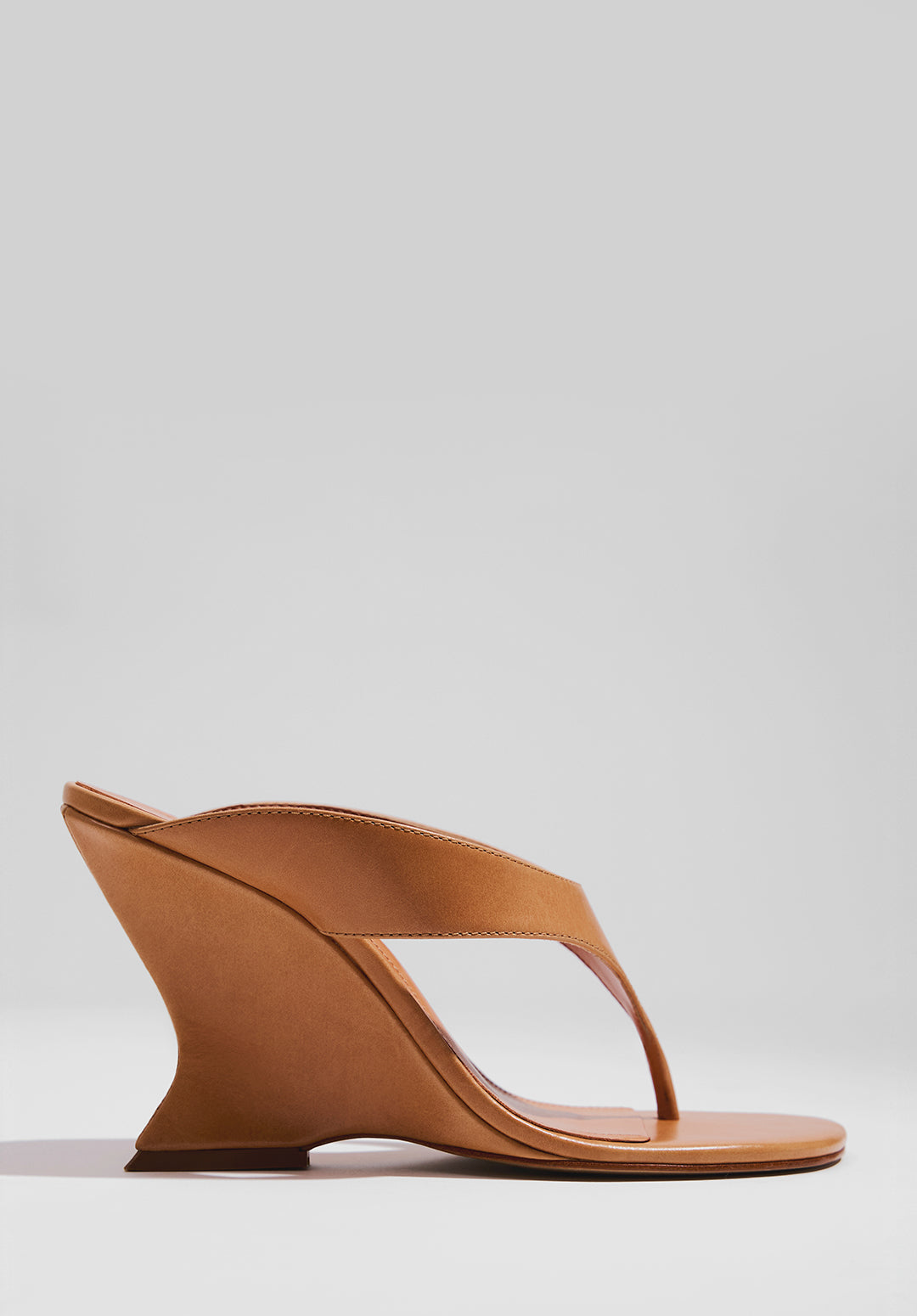 Brown sandal featuring a unique sculptural curved heel design, highlighting artistic and contemporary high heel styles.